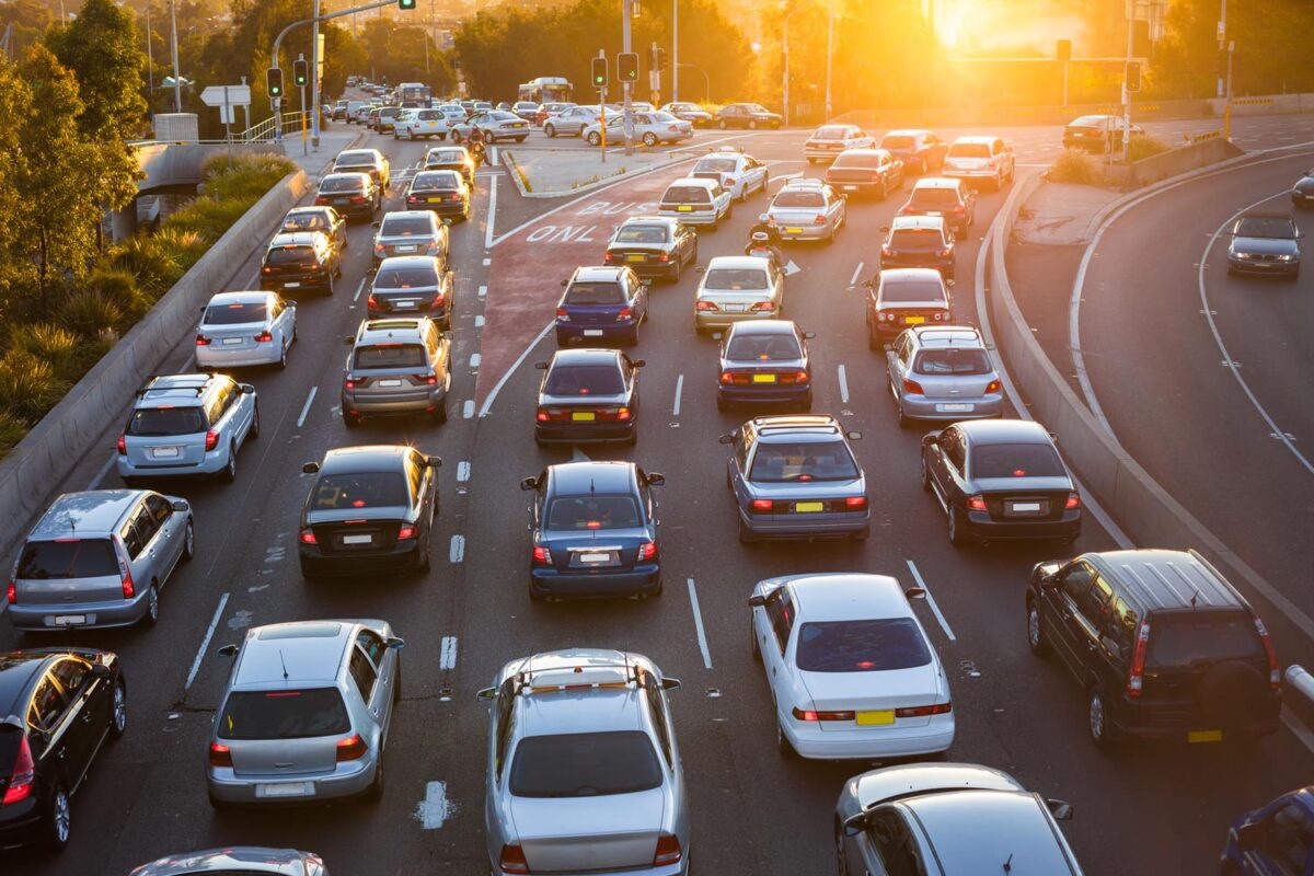 Cars stuck in heavy rush hour traffic on a multi-lane city highway at sunset